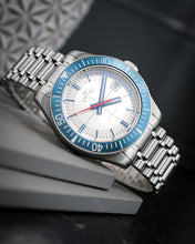 Load image into Gallery viewer, Silver watch with blue bezel and white face on a dark background