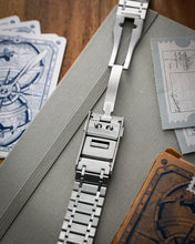 Load image into Gallery viewer, Metallic watch strap on a textured surface with playing cards and a wooden box.
