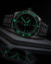 Load image into Gallery viewer, Black wristwatch with green glowing face on a dark background
