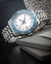 Load image into Gallery viewer, Silver watch with blue bezel on a dark surface
