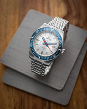Load image into Gallery viewer, Silver watch with blue bezel and white face on a wooden surface
